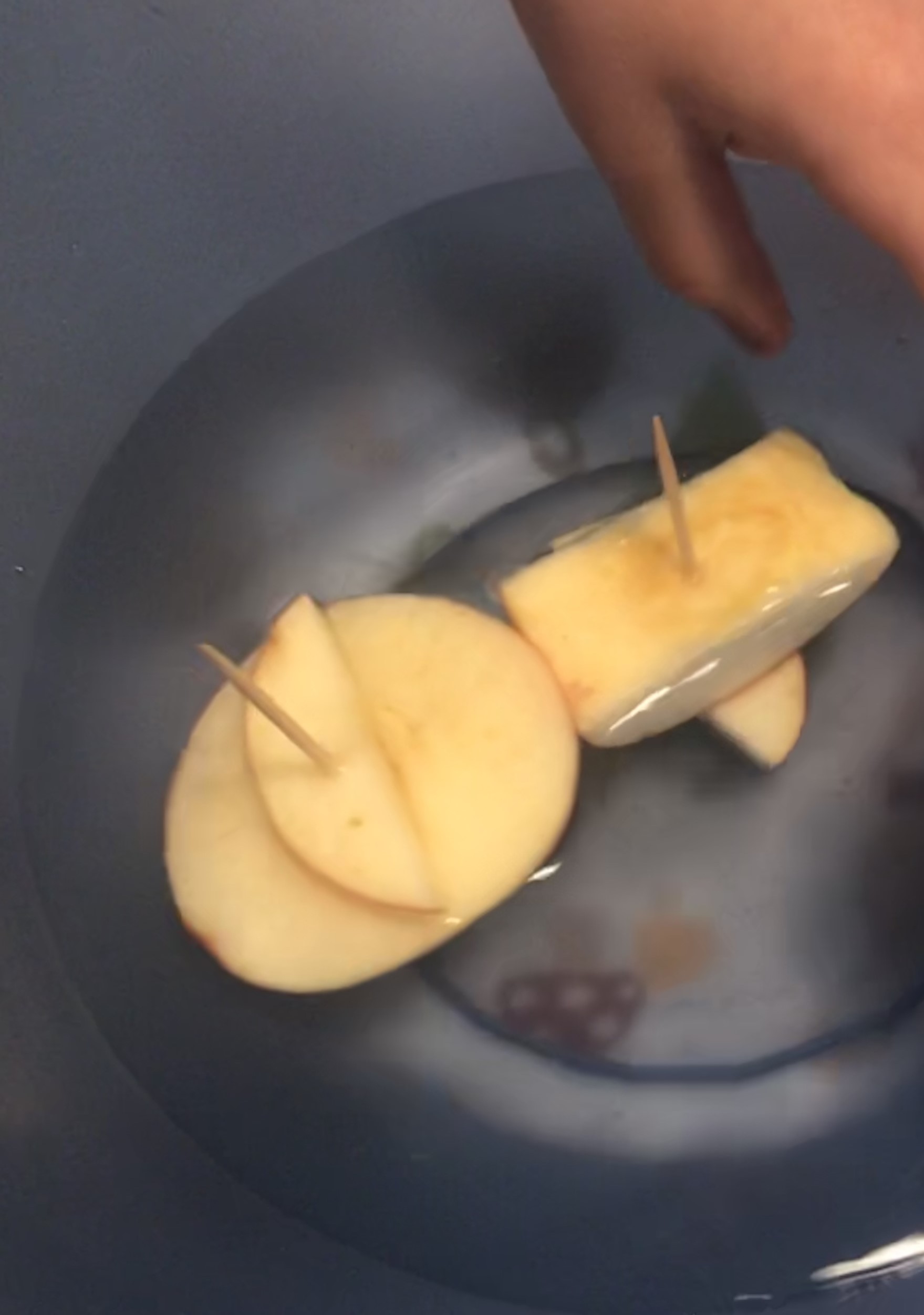 Small boats made of apple slices and toothpicks, float in a bowl of water.