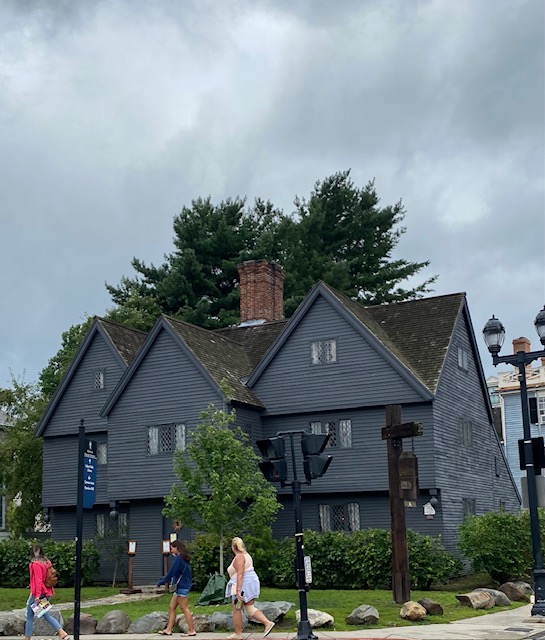 The Witch House in Salem, MA. A large dark grey home sits among trees.