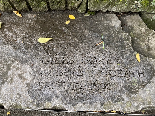Cement bench inscribed in memorial of Giles Corey in Salem, MA