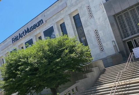 Picture of a large white building. A large wide staircase leads up to doors. Large black letters say, "Frist Art Museum". There is a wide but short green tree in front of the building.