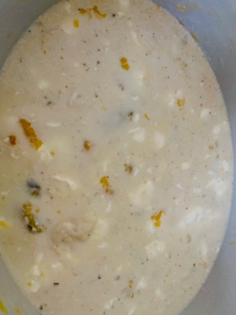 A cream colored soup with white spots and darker spots in a white bowl.