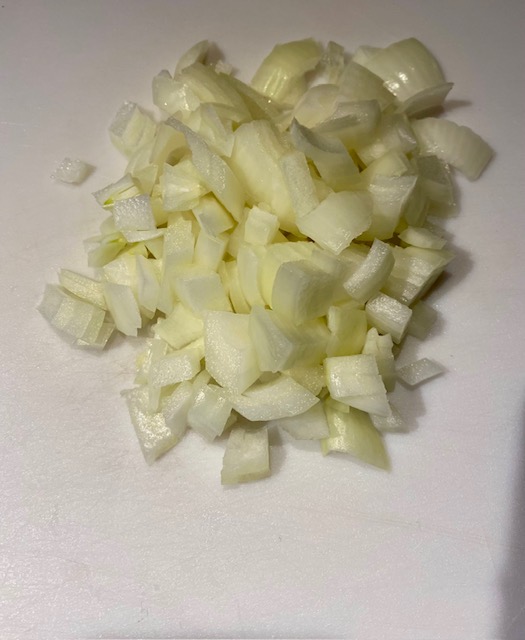 A pile of sweet white onion chopped into 1/2 inch pieces on a white background.