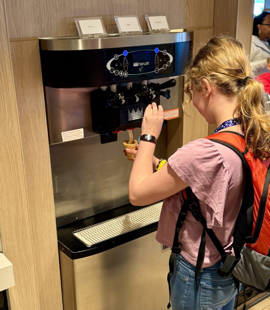 A girl uses the soft serve ice cream machine in the Garden Cafe restaurant on the NCL Bliss.