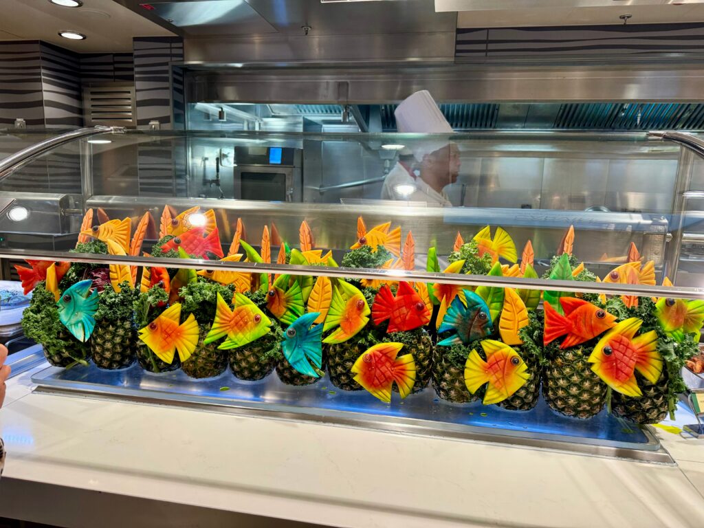 Pineapples on a buffet line in the Garden Cafe one of many restaurants on the NCL Bliss.  The pineapples are carved into the designs of tropical fish and then dyed different bright colors.  