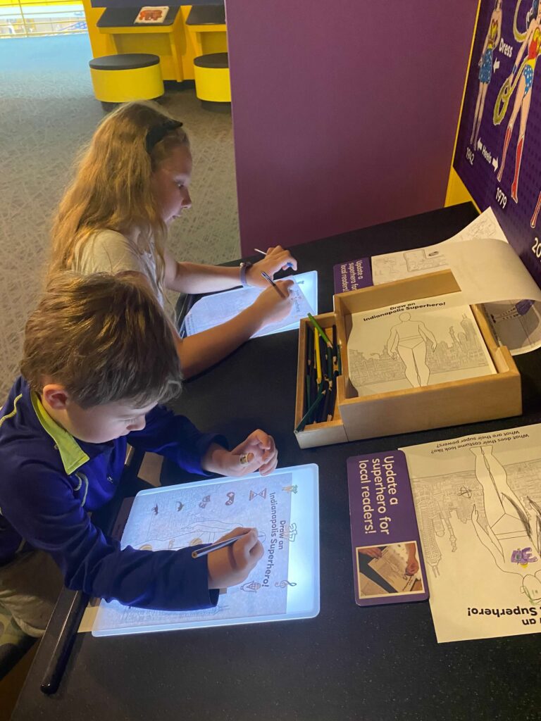 Two children draw comics on a light table at the Childrens Museum of Indianapolis