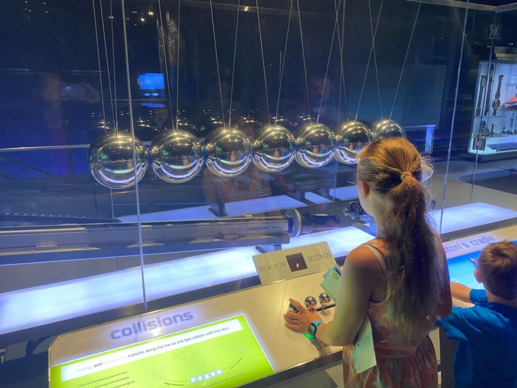 A child looks at a Newton's Cradle made of seven silver bowling balls at the Griffin Museum of Science and Industry.