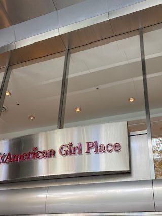 Outdoor signage for the American Girl Place.  A silver building and sign with pink lettering.