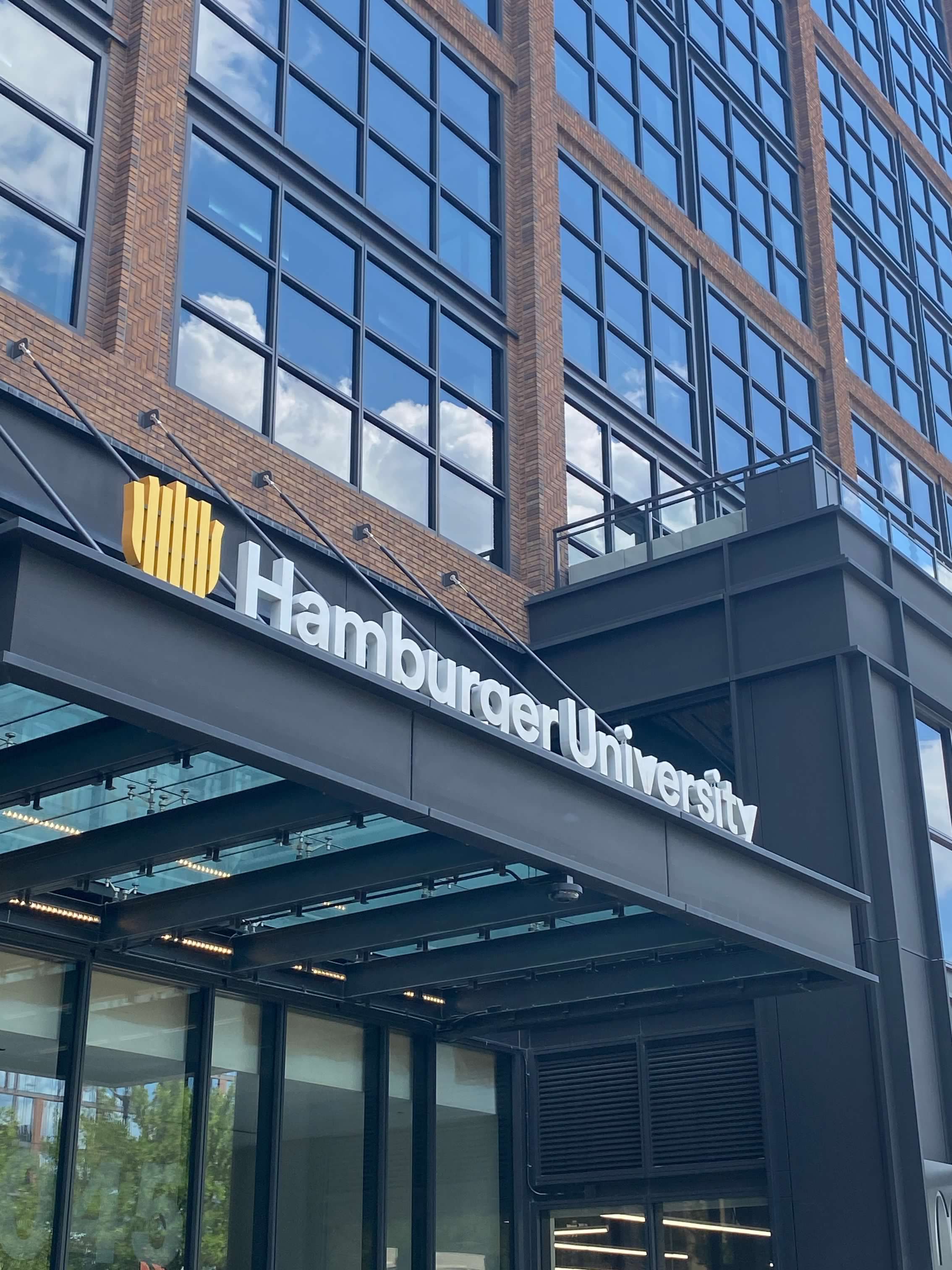 Chicago McDonalds-A large bricked building with several large windows stretching several stories up.  A sign reads "Hamburger University" in white lettering and has a logo that looks like french fries on the front awning.  