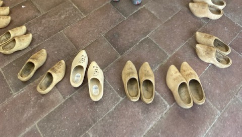 A semi circle of Dutch wooden shoes is displayed on a brick floor.