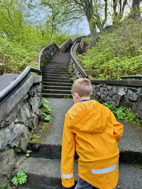 A young boy in a yellow rain slicker climbs the steps to the top of Baranof Castle in Sitka, Alaska.