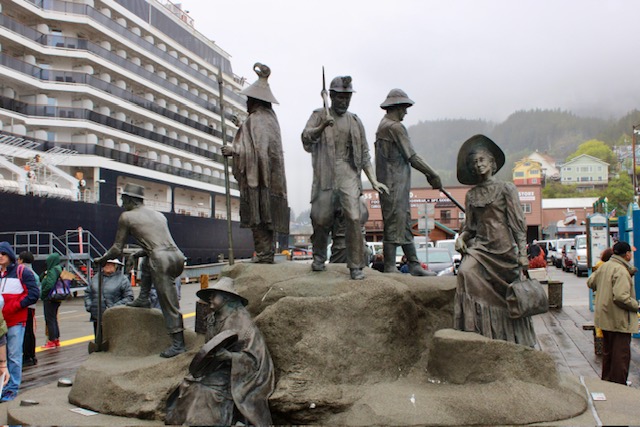 A large rock with several bronze figures on and around it sits near the cruise ship berths in Ketchikan, Alaska. 