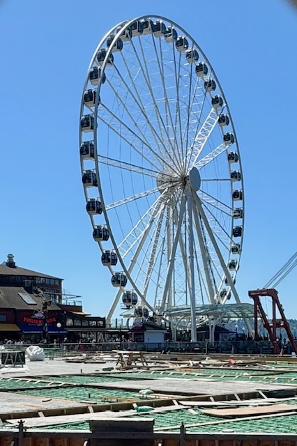 Seattle 's Great Wheel: a huge Ferris Wheel with a blue sky behind it. 