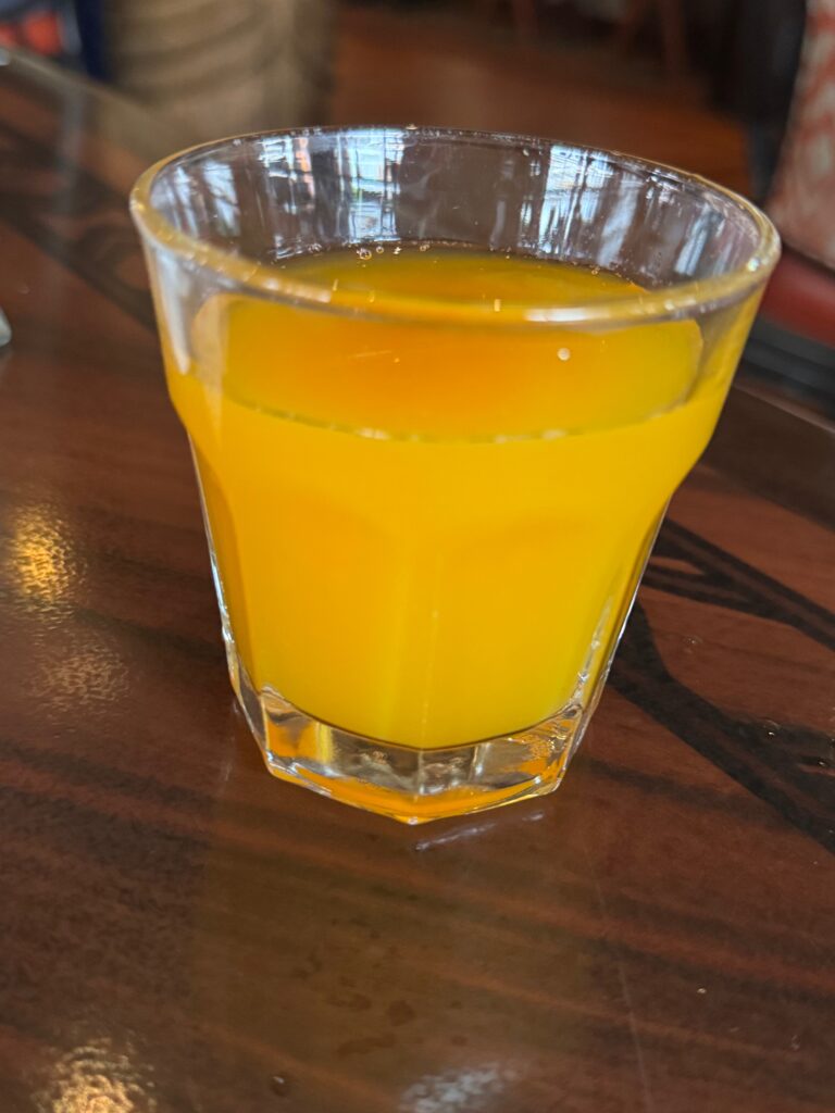 A juice glass filled with orange liquid.