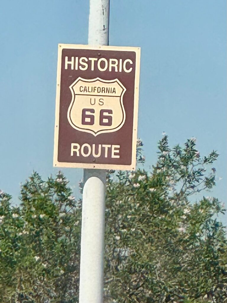 A brown road sign marking the historic Route 66 in California. 